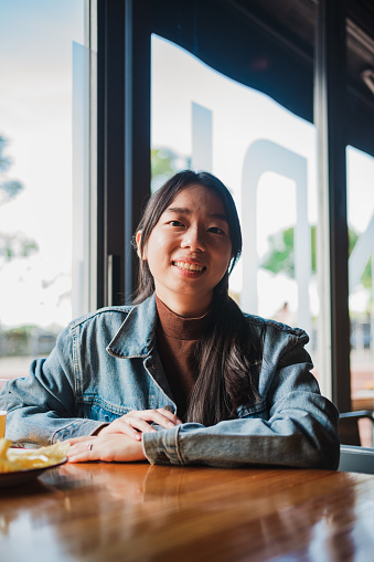 Portrait of smiling asian girl in a bar looking at camera.