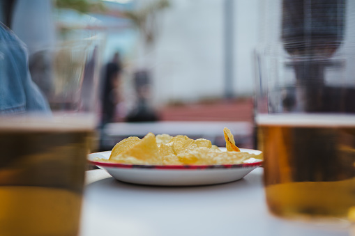 Close up of beer glasses and chips on a bar table at the terrace