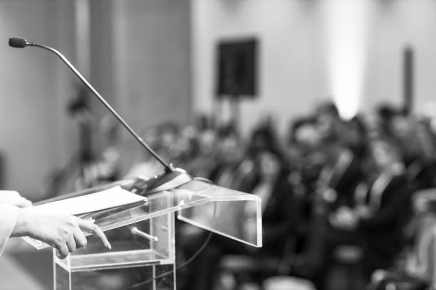 istock Woman coach at business seminar, conference, presentation or coaching training, blurred audience in background 1459114287
