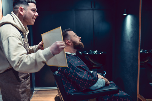 Smiling Barber Showing Customer Back Of Head And Nape Of Neck Haircut With Mirror