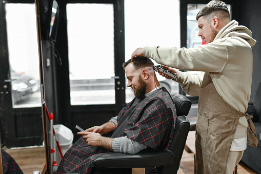 Relaxed Customer Browsing Haircut Ideas While Getting Barber Shop Treatment