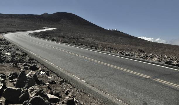 the winding road leading towards the summit of haleakalā, with the haleakalā observatory in the background. stock photo