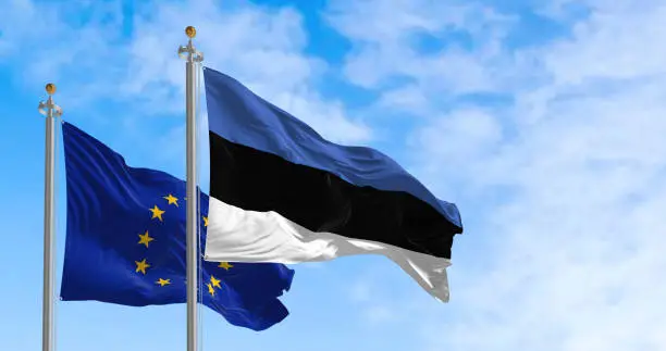 The flags of Estonia and the European Union waving together on a clear day. Estonia became a member of the European Union on May 1, 2004. Realistic 3d illustration. International treaty and diplomacy