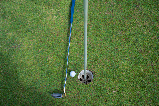 Golf ball and golf club on green in the evening golf course with sunshine in thailand.