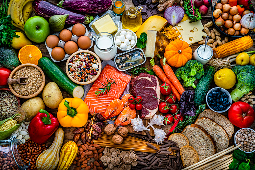Overhead view of a large group of all sort of food for a well balanced and healthy diet of proteins, dietary fiber, carbohydrates, vitamins and minerals. The composition includes fruits, vegetables, fish, raw meat, beans, seeds and nuts, pasta, cooking oil, spices and dairy products. High resolution 42Mp studio digital capture taken with SONY A7rII and Zeiss Batis 40mm F2.0 CF lens