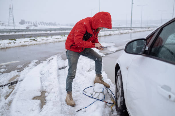 istock Young Adult Man Talking Over Mobile Phone While Mounting Tire Chains 1459132926