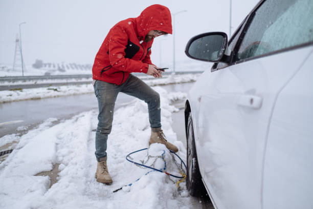 istock Young Adult Man Talking Over Mobile Phone While Mounting Tire Chains 1459133159