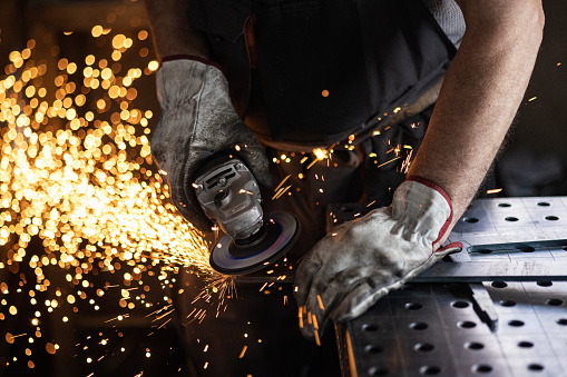 Welder at work. Man in a protective mask. The welder makes seams on the metal. Sparks and smoke when welding.