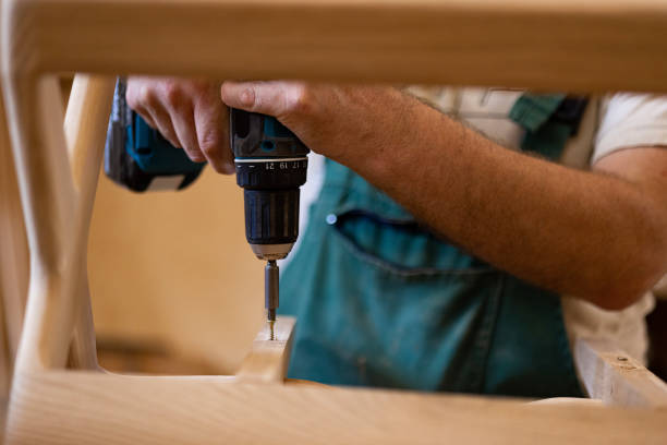 istock Close up of male carpenter using drill while working on wooden structure. 1459135464