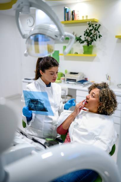istock Dentist explaining tooth x-rays to a female patient 1459135652