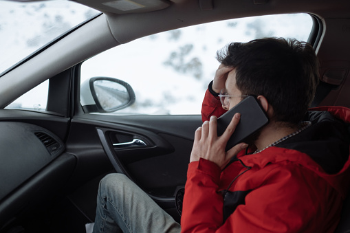 Transportation, winter, weather, people and vehicle concept - man cleaning snow from car with brush