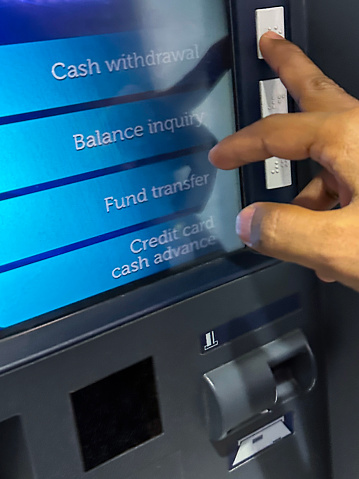 Stock photo showing close-up view of cash withdrawal being selected with middle finger of unrecognisable person at a cashpoint (ATM - automatic teller machine). Cash machine fraud is an ongoing problem for banks, with a growing percentage of debit and credit cards being cloned or stolen.