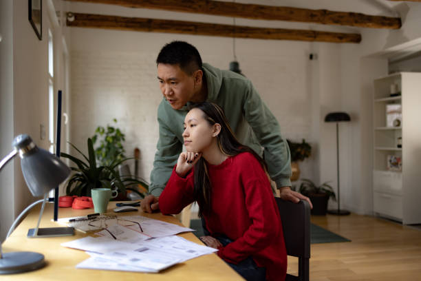 istock Young Asian couple e-banking over PC at home. 1459139004