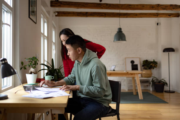 istock Chinese couple paying their bills online over a computer at home. 1459139143