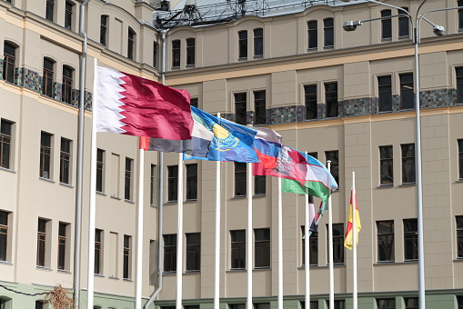 Flags waving in the wind at the Revolution Square in Moscow. On the picture we see the flags of Qatar, South Ossetia, Yemen, UAE, Kazakhstan, Uzbekistan, Egypt, Iraq and Sudan. In the background we see the building of a hotel.