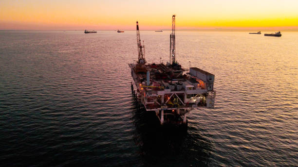 드론은 먼 배경에 카탈리나 섬이 있는 황혼의 맑은 저녁에 잔잔한 바다에서 대형 산업용 가스 및 석유 해양 시추 장비를 봅니다. - oil rig sea oil storm 뉴스 사진 이미지