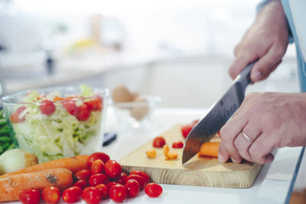 istock Chef at home using a knife cutting fresh raw vegetables. Cooker at home making a healthy vegetable meal, cutting up veggies - food and drink 4k footage - One man preparing salads in the kitchen 1459141123