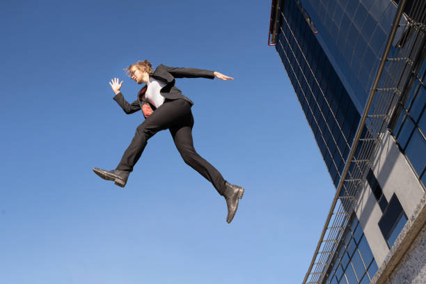istock business man doing a jump with blue sky background suit clothes between buildings 1459141183