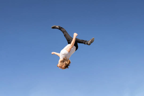 istock caucasian blond boy doing a backflip and parkour with blue sky in the background 1459141208