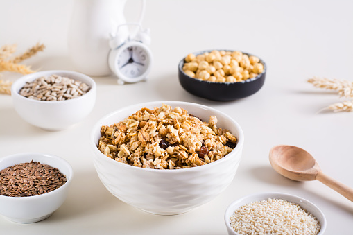 Baked granola in a bowl and different seeds in bowls on the table. Healthy breakfast.