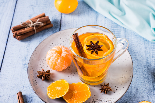 Fresh tangerine tea with cinnamon in a cup on the table. Vitamin drink.