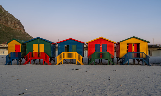 Vibrant sunrise over the colorfully painted beach huts on \nMuizenberg Beach at the base of the Cape Peninsula outside Cape Town, South Africa.