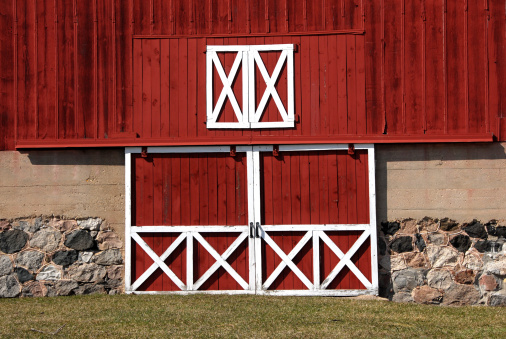 Doors of a red barn with stone foundation.
