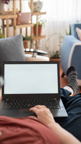 istock Woman using laptop with white screen while lying on sofa at home , mock up screen 1459145474