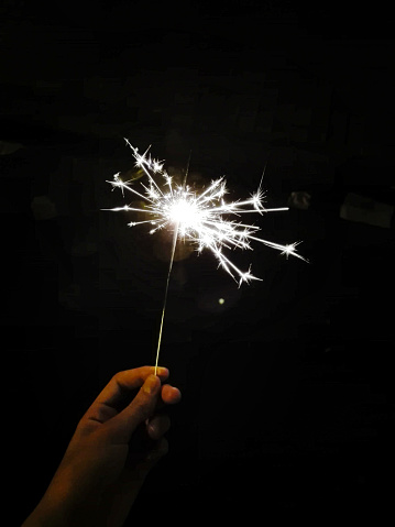 hand holding a burning sparkler on black background
