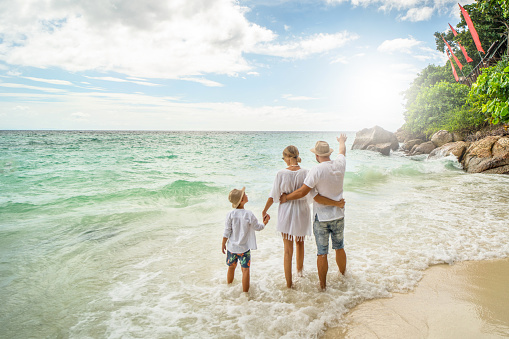 Happy family on the beach having fun on summer vacation. Father mother and one child enjoying sun. Holiday travel concept. Tourism.