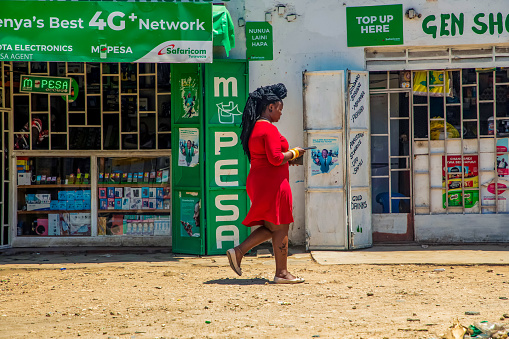 DIani Mombasa Kenya 18 oktober 2019. small traditional African street market. a girl in a bright red dress walks past a shop