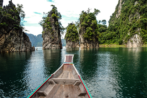 Wooden Thai traditional long tail boat on a lake with limestone mountains in Khao Sok National Park, Surat Thani Province, Thailand. Beautiful landscape. Power of nature.