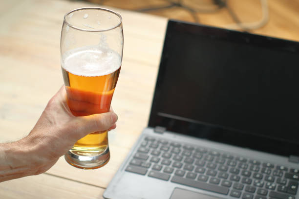 istock person holding a beer mug next to a laptop 1459152796
