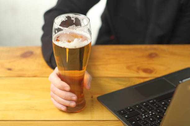 istock mug with beer in hand next to laptop 1459152837
