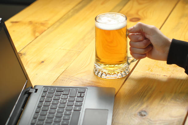 istock mug with beer in hand next to laptop 1459152861