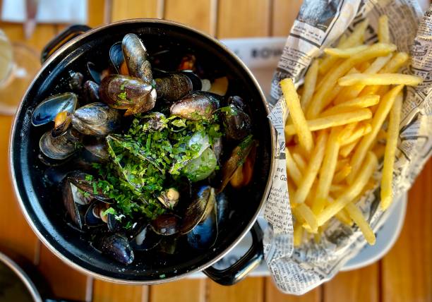 Moules frites Mussels in vegetable white wine stock served with French fries moules frites stock pictures, royalty-free photos & images