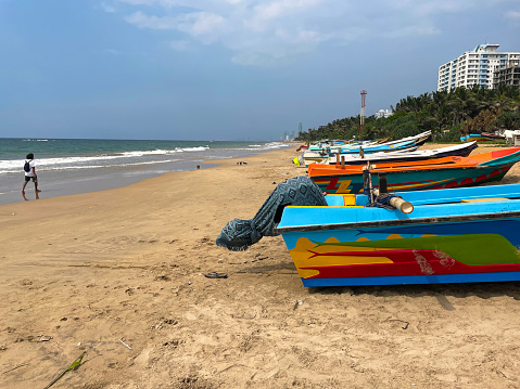 Stock photo showing close-up view of Mount Lavinia Beach, Sri Lanka with \nvibrant coloured fishing boats in a row on the sand. Each morning at sunrise, the fishermen sail out with their boats and carefully set the large net, trawling the water and pulling it to the shore, catching small baby fish, as well as tuna, mackerel and Indian kingfish.