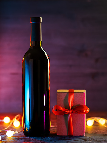 A bottle of red wine and a gift box with a red ribbon.