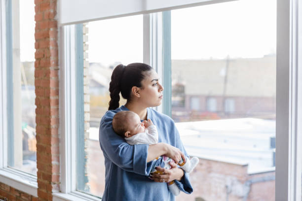 istock Holding baby, depressed mom looks out window 1459157310