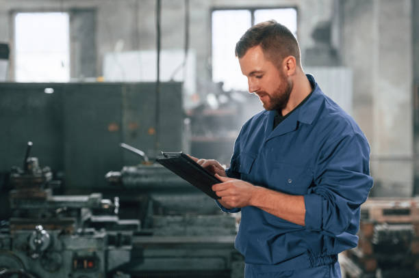 istock Front view. Factory worker in blue uniform is indoors 1459158138
