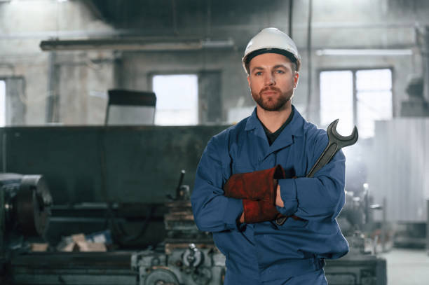 istock Front view. Factory worker in blue uniform is indoors 1459158154
