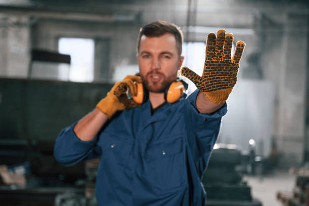 istock Showing stop gesture by a hand. Factory worker in blue uniform is indoors 1459159335