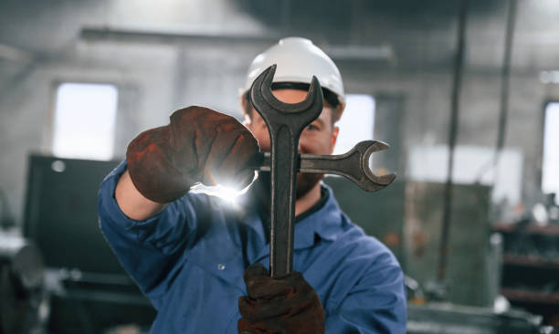 istock Hands gesture. With wrenches. Factory worker in blue uniform is indoors 1459159425