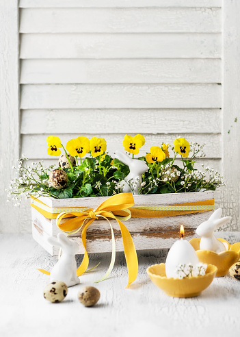 Handmade decoration made with yellow viola flowers in the old vintage wooden box for Easter. Copy space. Floristic concept.