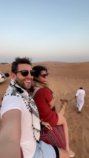 Couple riding a camel in the desert - point of view
