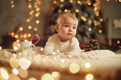 Front view. Beautiful portrait. Cute little baby is at home. New year decorations. Conception of holidays.