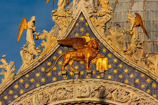 Winged lion sculpture (symbol of Venice) on St. Mark's basilica facade in center of Venice, Italy