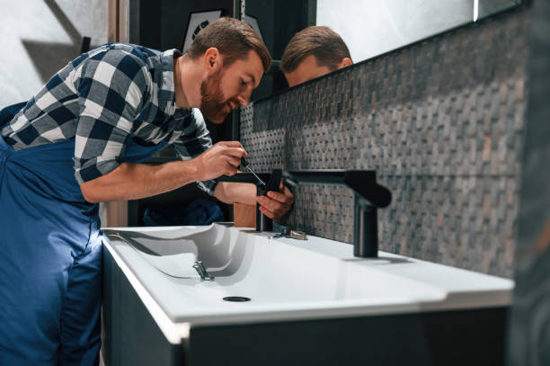 istock Side view. Fixing water tap. Plumber in blue uniform is at work in the bathroom 1459162565