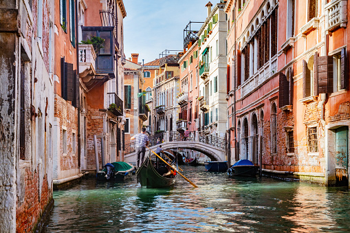 Canal in Venice, Italy with gondolier rowing gondola. Romantic Venetian waterway
