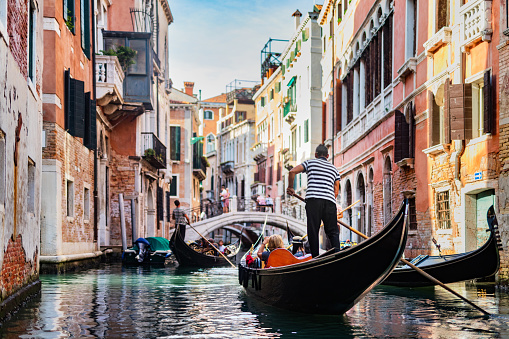 Gondolier rowing gondola on canal in Venice, Italy.